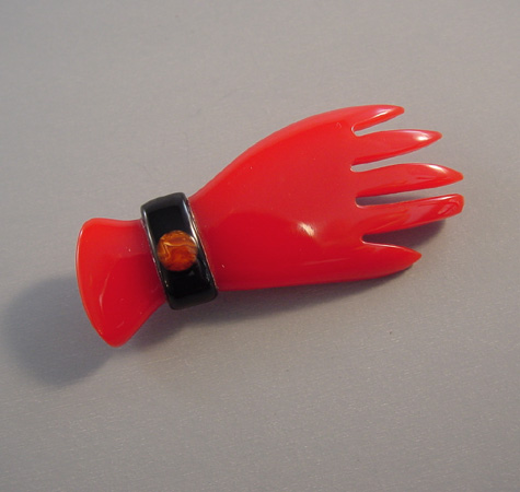 SHULTZ bakelite red hand brooch wearing a bangle bracelet