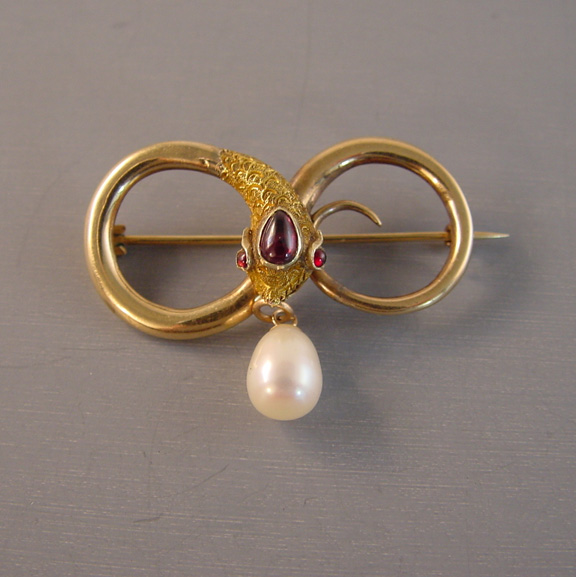 VICTORIAN 15 karat yellow gold snake infinity brooch with a garnet cabochon head and eyes