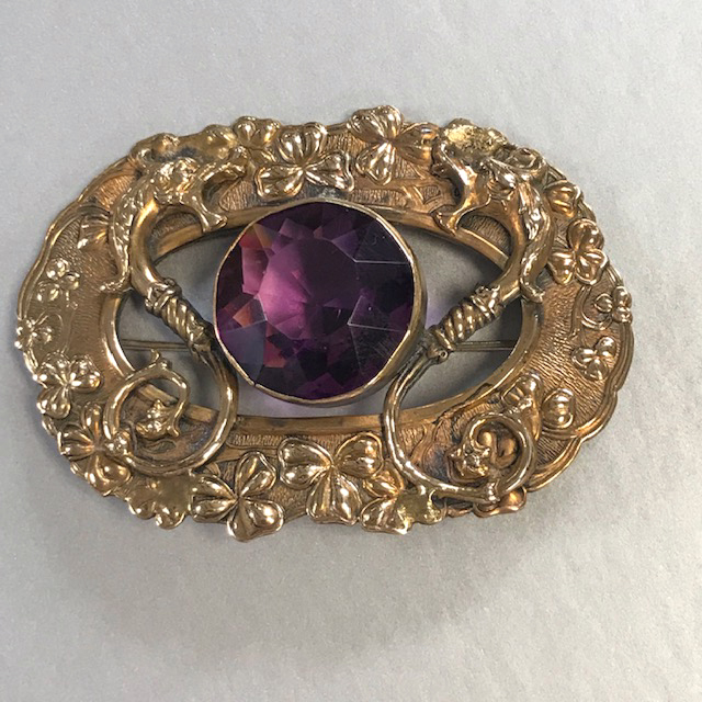 GRIFFONS figural sash brooch with a purple center rhinestone surrounded by griffons and clovers