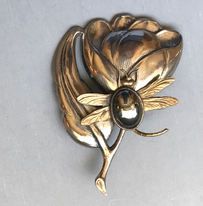INSECT or bug on a flower and leaf brooch, possibly a dragonfly or a bee, with an oval hematite set on a silver metal leaf