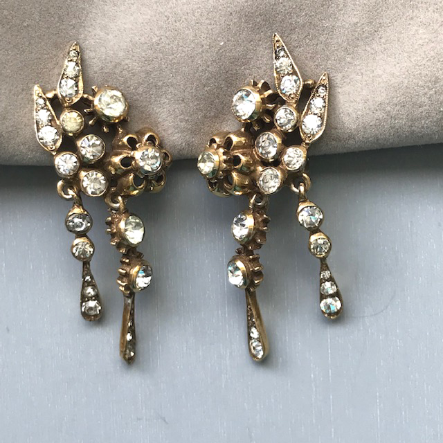 DEROSA dangling pendant style earrings with clear rhinestones set in gold tone metal, open flower design