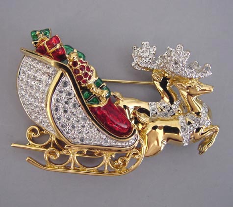 SWAROVSKI Christmas Santa’s sleigh brooch with a clear rhinestone pave  sleigh and deer and enameled red and green packages