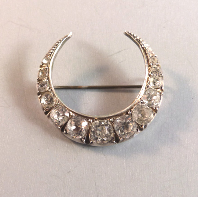 VICTORIAN crescent moon brooch with clear cushion cut pastes set in a hollow sterling silver crescent