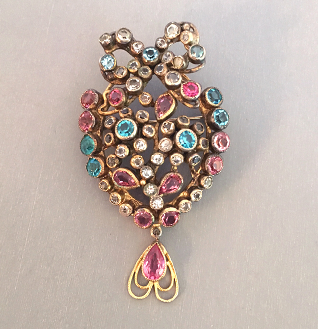 HOBE heart and bow brooch with a drop suspended from the bottom, it is aqua, pink and clear