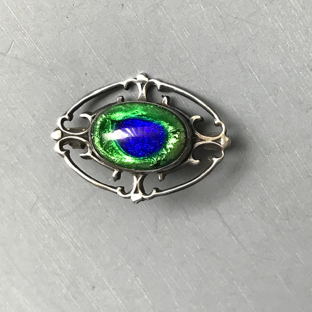 PEACOCK EYE antique pin with an oval eye set in silver metal with back to back “C’s” designs on four sides