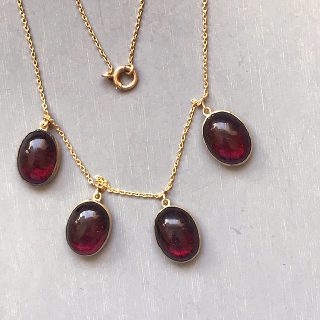 NECKLACE of lovely garnet colored oval glass cabochons in a gold filled setting and on an 18k yellow gold chain