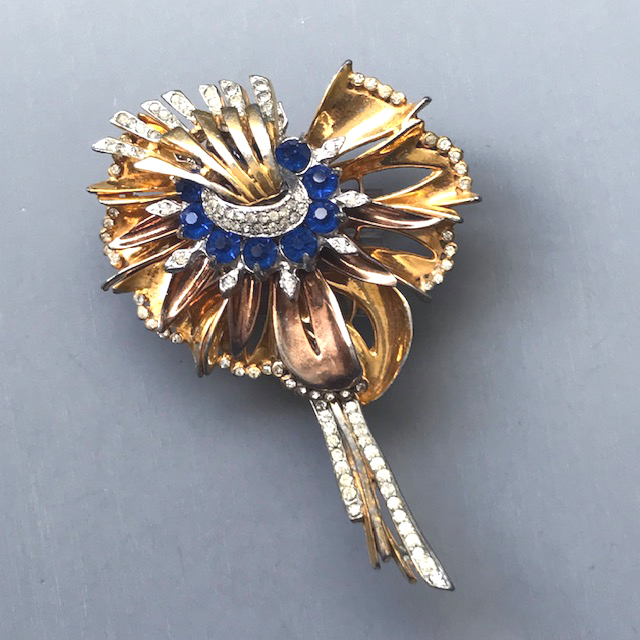 REINAD signed flower brooch with multiple layers in bright blue and clear rhinestones, the first layers of a rose gold wash and the others of yellow gold