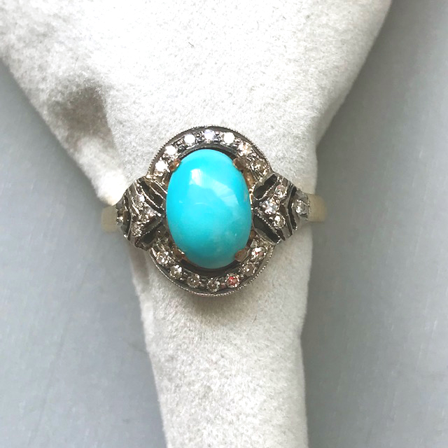 TURQUOISE cabochon ring with a halo of  diamonds in an 18 karat yellow and white gold setting