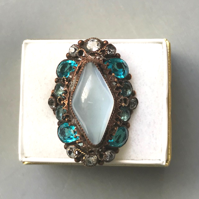 HOBE attributed ring with unusual pale blue moonstone glass cabochon in a rounded diamond shape surrounded with unfoiled aqua and clear rhinestones and in a gold plated sterling silver setting