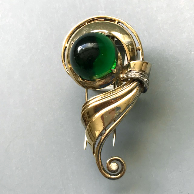 DEROSA fur clip with a glowing emerald green glass cabochon center and clear rhinestone accents in a gold plated sterling silver setting, marked only “sterling”