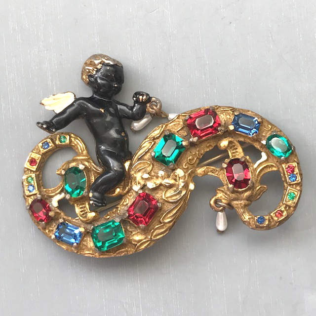 CHERUB riding on an ocean wave brooch with colorful rhinestones set in a gold tone metal
