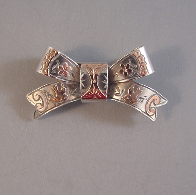VICTORIAN antique sterling silver bow brooch with rose gold overlay birds, flowers and etched designs, hallmarked for the maker “WCM” for William Clark Manton date 1901