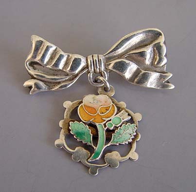 VICTORIAN bow and charm brooch with orange and green enameled flower and a bow top