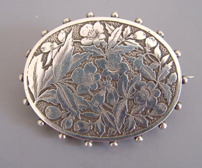 VICTORIAN floral locket brooch, and antique sterling silver oval brooch with etched designs of flowers and leaves and a detailed beaded edge