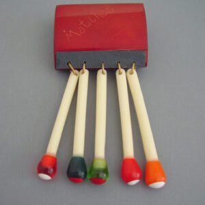 MOE by Jackie Weeks bakelite and plastic book of matches brooch with striker and dangling multi-colored matches, late 1990s